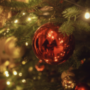 A traditional Christmas decoration Red glass bauble hanging among fir branches and warm Christmas lights