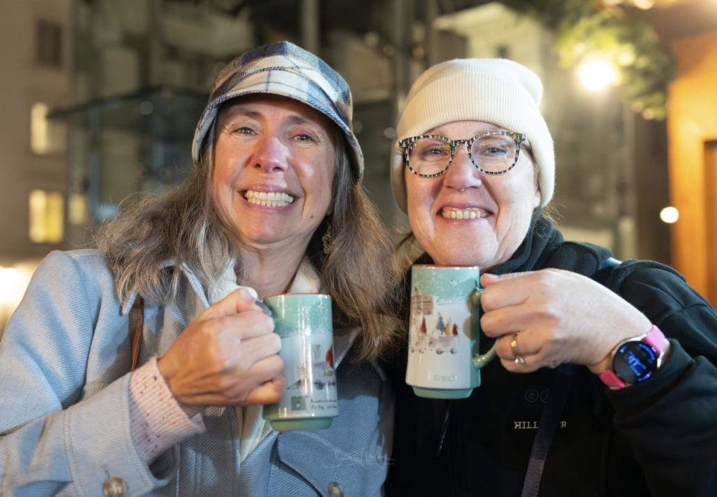 A festive punch break Two smiling guests holding green mugs during a Vienna Christmas tour