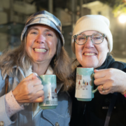 A festive punch break Two smiling guests holding green mugs during a Vienna Christmas tour