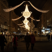 Christmas lights on the Graben People walking beneath golden chandelier Christmas lights on Vienna’s Graben